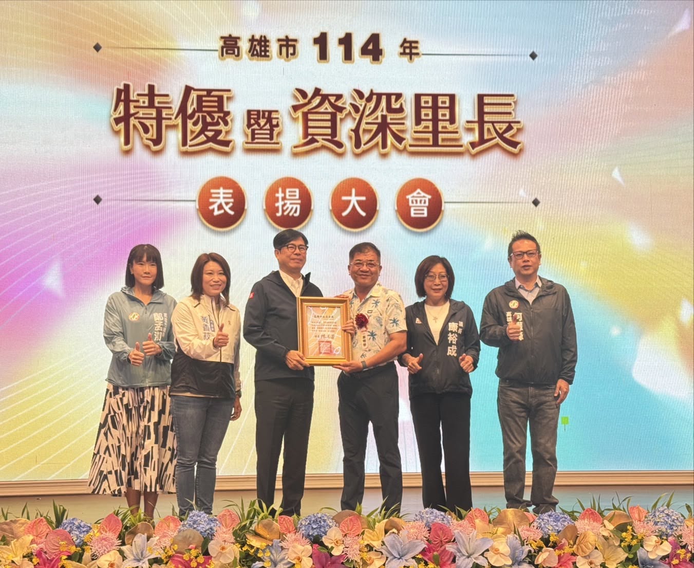 謝明學於高雄市114年特優暨資深里長表揚大會，手持獎狀與現場來賓合影